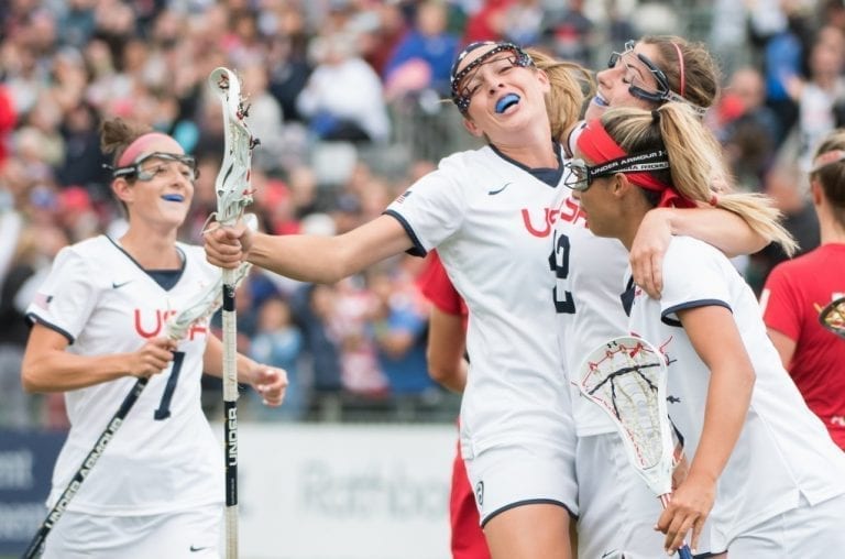 USA's Taylor Cummings(facing) celebrates with Kayla Treanor(12) and Alex Aust(nearest the camera) after Treanor had scored with an over- the shoulder shot at the 2017 FIL Rathbones Women's Lacrosse World Cup at Surrey Sports Park, Guilford, Surrey, UK, 15th July 2017